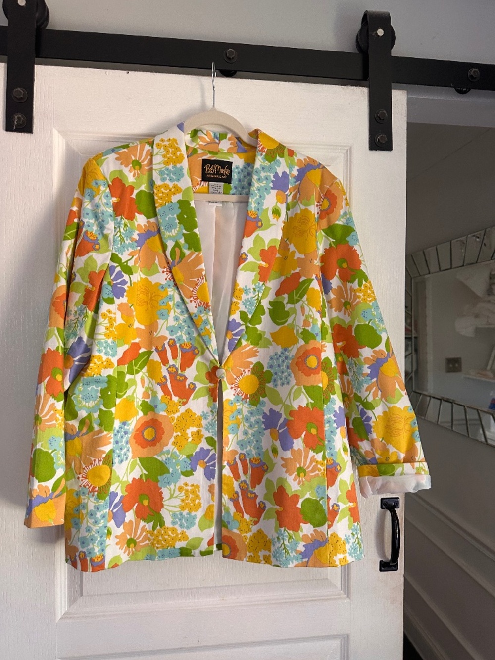 That vibrant 1960s or 1970s-style floral print blazer appears to be a piece from